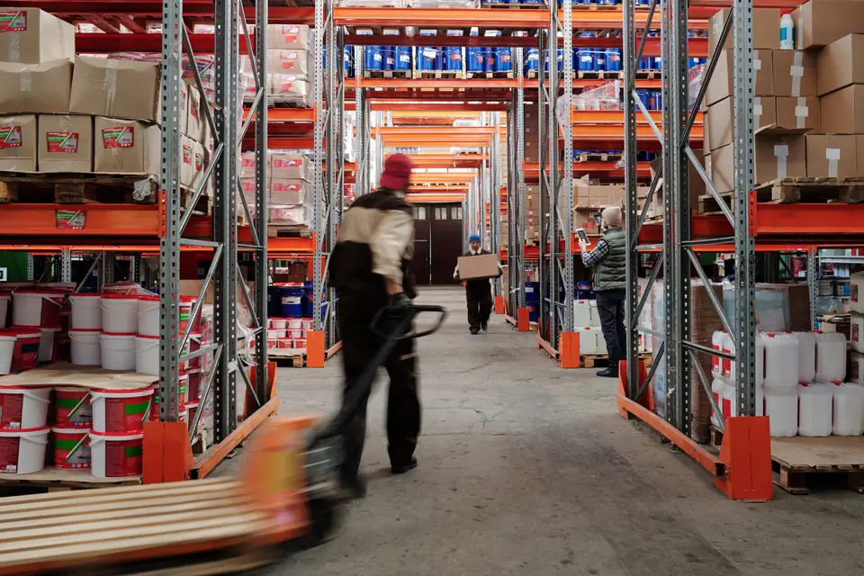 Personal moviendo mercadería en los pasillos de un depósito.